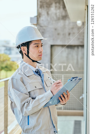 一名年輕的男建築工人在檢查某件東西 126551262