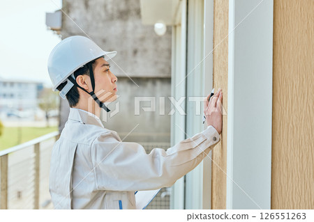 一名年輕的男建築工人在檢查某件東西 126551263