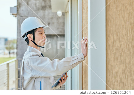 一名年輕的男建築工人在檢查某件東西 126551264