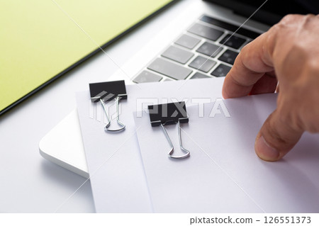 Documents clipped together and a computer Documents clipped together and a computer 126551373