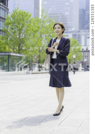 Young business woman walking through an office district, vertical position Young business woman walking through an office district, vertical position 126551383