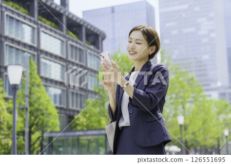 一位年輕的女商人在辦公區用智慧型手機搜索 一位年輕的女商人在辦公區用智慧型手機搜索 126551695