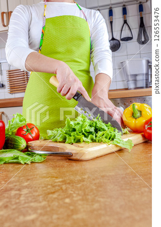 Woman chopping lettuce on cutting board... Woman chopping lettuce on cutting board... 126553476