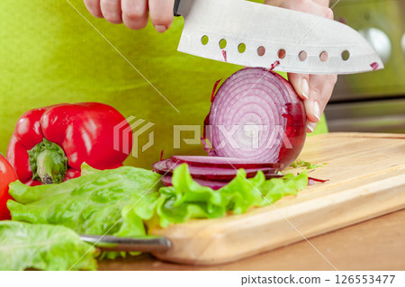 Woman chopping red onion on cutting board... Woman chopping red onion on cutting board... 126553477