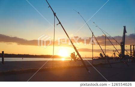 Fishing rod, spinning reel on the background pier river bank. Sunrise. Fog against the backdrop of lake. Misty morning. wild nature. The concept of rural getaway. Article about fishing day. 126554026