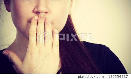 Woman covering her mouth with hand 126554387