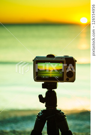 Camera taking picture film of sunrise over sea surface Camera taking picture film of sunrise over sea surface 126554956