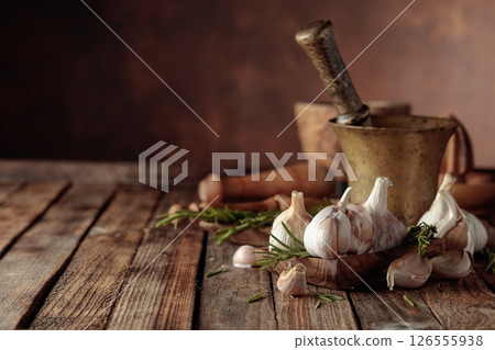 Fresh garlic bulbs with rosemary on a wooden table. 126555938