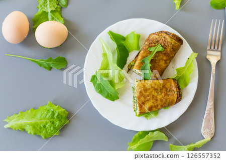 Appetizing omelette with greens and arugula on a white plate 126557352