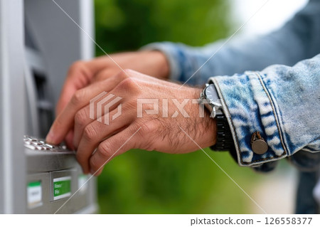 Male customer using ATM in casual denim jacket 126558377