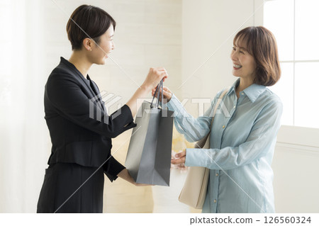 Woman handing over a shopping bag 126560324