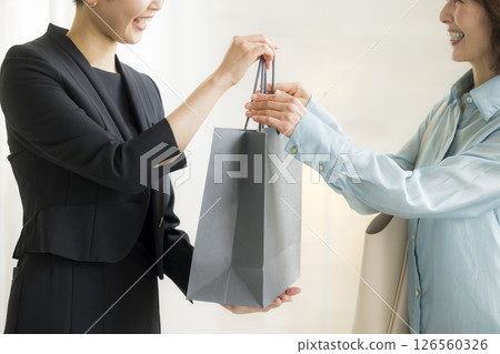 Woman handing over a shopping bag Woman handing over a shopping bag 126560326