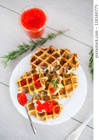 Potato waffles with red caviar on a wooden table Potato waffles with red caviar on a wooden table 126560775