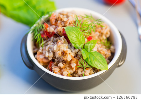 Cooked buckwheat with vegetables on a gray background Cooked buckwheat with vegetables on a gray background 126560785
