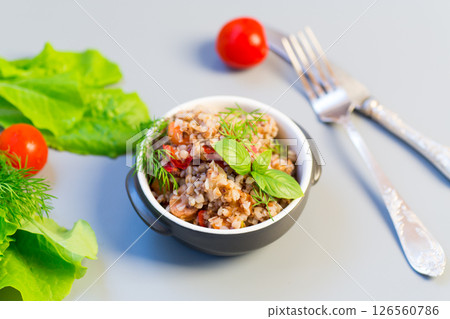 Boiled buckwheat with vegetables on a gray background Boiled buckwheat with vegetables on a gray background 126560786