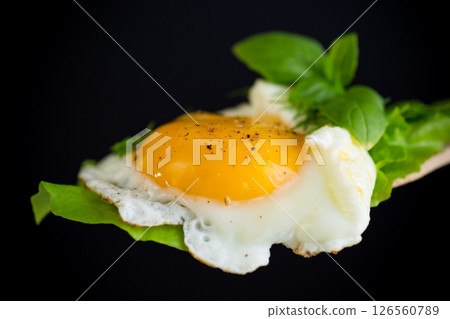 Appetizing fried egg with greens on a wooden spatula Appetizing fried egg with greens on a wooden spatula 126560789