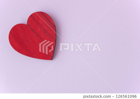 Red wood heart on the pink paper background with space for text. Concept with love sign for card. Red wood heart on the pink paper background with space for text. Concept with love sign for card. 126561096