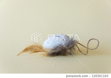 Easter little egg with feather on beige natural background. Easter concept. Easter little egg with feather on beige natural background. Easter concept. 126561103