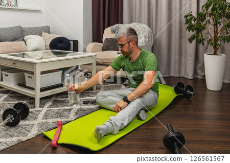 Man exercising at home with weights and water bottle 126561567