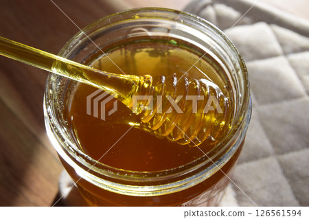 Honey jar with honeycomb and yellow spoon stay on the wood table. 126561594