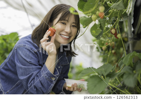 A woman holding a strawberry with a smile 126562313