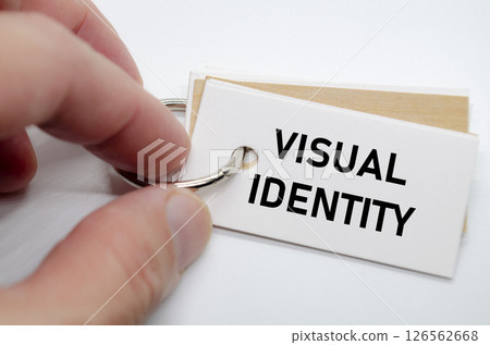 Visual identity concept presented on white notepad with hand holding it in clean workspace. Visual identity concept presented on white notepad with hand holding it in clean workspace. 126562668