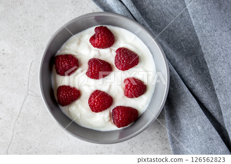 Natural fresh greek yogurt with red raspberry berries in dark plate and napkin for healthy breakfast.  126562823