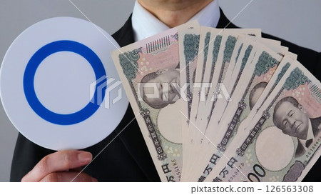 A businessman holding the new 10,000 yen note and a round stick A businessman holding the new 10,000 yen note and a round stick 126563308