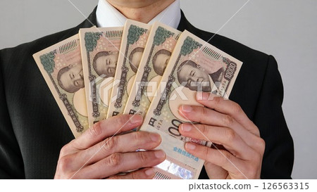 Japanese businessman holding a stack of bills 126563315