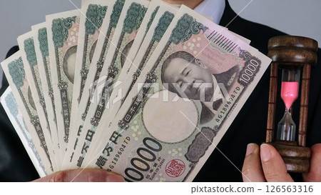 Person holding an hourglass and the new 10,000 yen note 126563316