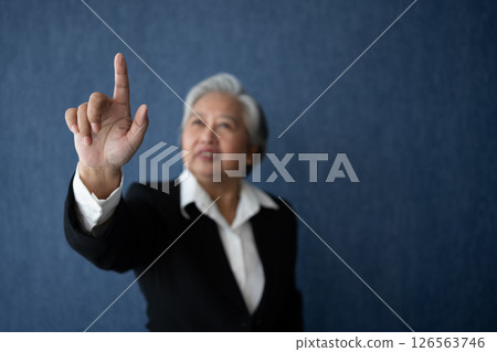 Portrait of middle aged business woman standing isolated on blue background and posing finger pointing and touching, looking at the camera with smile, Successful businesswoman, ceo, director, manager Portrait of middle aged business woman standing isolated on blue background and posing finger pointing and touching, looking at the camera with smile, Successful businesswoman, ceo, director, manager 126563746