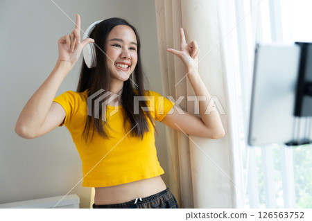 Asian women and beautiful bloggers wear headphones dancing videos by smartphone cameras. Creator vlogger talent dancing enjoys hobby content recording show video sharing on social media. Asian women and beautiful bloggers wear headphones dancing videos by smartphone cameras. Creator vlogger talent dancing enjoys hobby content recording show video sharing on social media. 126563752