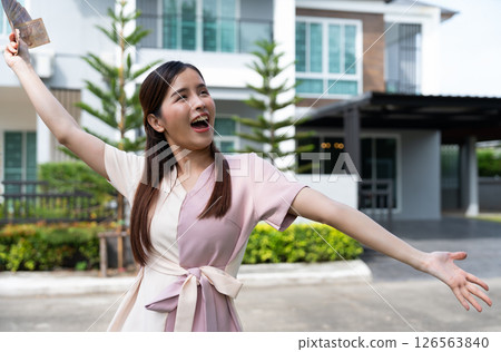 Portrait of happy attractive Asian women holding a lot of banknotes in front of home to celebrate and Pay the final installment of the house, Loans for real estate concept, Smiling young successful Portrait of happy attractive Asian women holding a lot of banknotes in front of home to celebrate and Pay the final installment of the house, Loans for real estate concept, Smiling young successful 126563840