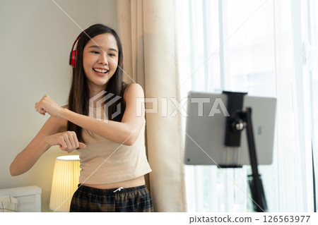 Asian women and beautiful bloggers wear headphones dancing videos by smartphone cameras. Creator vlogger talent dancing enjoys hobby content recording show video sharing on social media. 126563977
