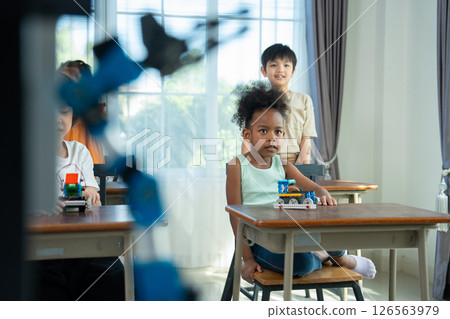 Young Engineers: multi ethnic Children engrossed in building and testing small robotics, showcasing curiosity, teamwork, and early STEM education. The focus robot and children hands-on engagement. Young Engineers: multi ethnic Children engrossed in building and testing small robotics, showcasing curiosity, teamwork, and early STEM education. The focus robot and children hands-on engagement. 126563979