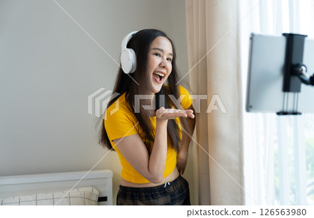 Asian women and beautiful bloggers wear headphones dancing videos by smartphone cameras. Creator vlogger talent dancing enjoys hobby content recording show video sharing on social media. 126563980