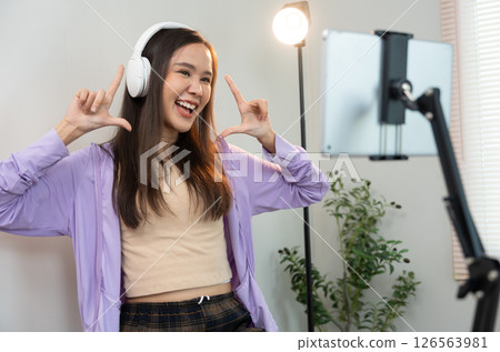 Asian women and beautiful bloggers wear headphones dancing videos by smartphone cameras. Creator vlogger talent dancing enjoys hobby content recording show video sharing on social media. 126563981
