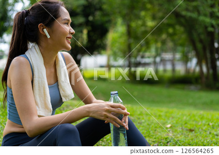 Asian young women drink water from a plastic bottle after exercises or sports. Asian woman running in garden. Beautiful fitness athlete woman drinking pure water after workout exercise on morning 126564265