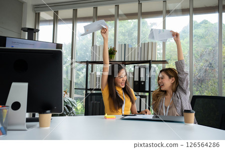 Asian smart Office or businesswoman excited successful business people, celebrating win. Two businesswoman looking at a monthly summary of sales that exceed sales targets and achieve profitable growth Asian smart Office or businesswoman excited successful business people, celebrating win. Two businesswoman looking at a monthly summary of sales that exceed sales targets and achieve profitable growth 126564286