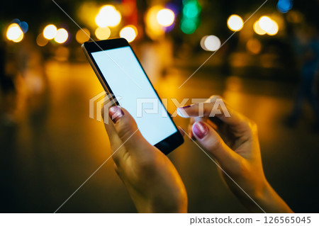 A woman is holding a cell phone and texting 126565045