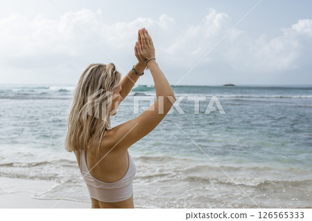 Do whatever pleases you. Shot of a young woman doing yoga at the beach. Do whatever pleases you. Shot of a young woman doing yoga at the beach. 126565333