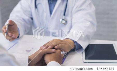 Doctor holding patient's hand for encouragement, empathy, cheering and support while medical examination. Bad news lessening, medicine and health care concept. Doctor holding patient's hand for encouragement, empathy, cheering and support while medical examination. Bad news lessening, medicine and health care concept. 126567185