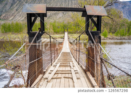 Wooden suspension footbridge crossing Chulyshman river near Katu Yaryk pass Altai Russia Remote connection point in wild mountain region Wooden suspension footbridge crossing Chulyshman river near Katu Yaryk pass Altai Russia Remote connection point in wild mountain region 126567298