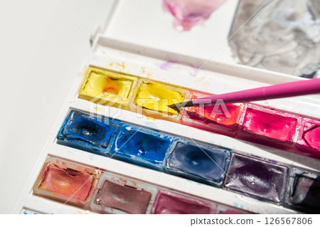 Bright watercolor palette with pink brush and vibrant mix of yellow, blue 126567806