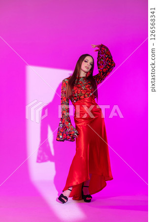A Stunning Fashion Model Posing in a Colorful Dress Against a Vibrant Pink Background A Stunning Fashion Model Posing in a Colorful Dress Against a Vibrant Pink Background 126568341