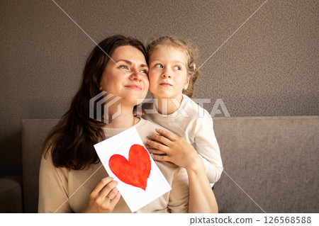 Mom and daughter celebrating 8 march, birthday, mothers day. Little preschool daughter surprising mom with handmade greeting card with painting. Mom and daughter celebrating 8 march, birthday, mothers day. Little preschool daughter surprising mom with handmade greeting card with painting. 126568588