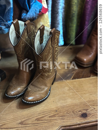 Vintage Brown Leather Cowboy Boots on Wooden Floor 126568659