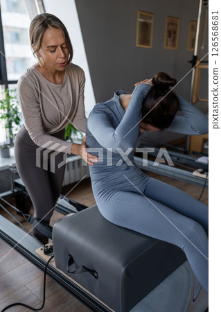 Woman doing rotation exercise on Pilates Reformer for the chest and back muscles, focusing on flexibility, strength, and control with determination 126568681
