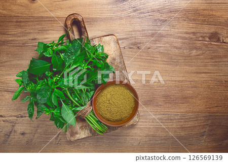 ground green basil, in a ceramic bowl, with a bouquet of fresh green basil, on the table, top view, no people, ground green basil, in a ceramic bowl, with a bouquet of fresh green basil, on the table, top view, no people, 126569139