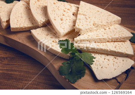 sliced Georgian cheese, factory grade, on a wooden board, top view, sliced Georgian cheese, factory grade, on a wooden board, top view, 126569164